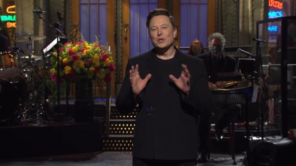 Elon Musk, in a black suit, hosting Saturday Night Live in May 2021
