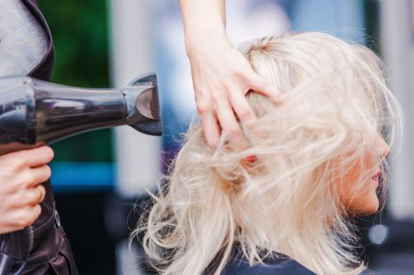 Blo<em></em>nde woman getting her hair blow dried at salon