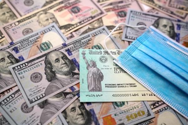 Pile of $50 and $100 bills with a blue surgical mask.