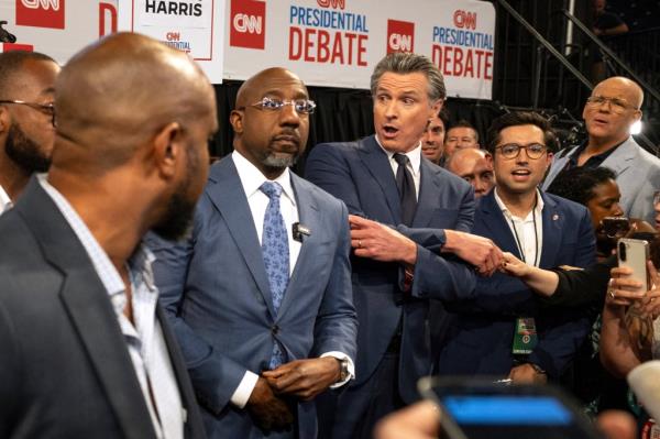 Members of the Democratic Party including US. Sen (D-GA) Raphael Warnock (2nd L) and California Governor Gavin Newsom (3rd L) speak to reporters in the spin room at the McCamish Pavilion on the Georgia Institute of Technology campus in Atlanta, Georgia,
