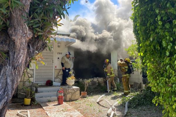 Firefighters standing outside Lynne Mishele's restored house that was previously destroyed by a car crash