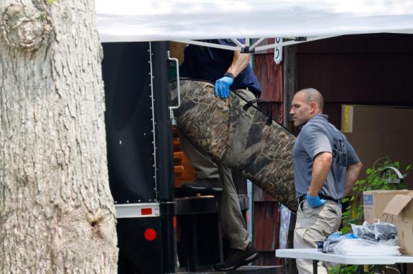 A camouflage rifle case is loaded o<em></em>nto a police truck.