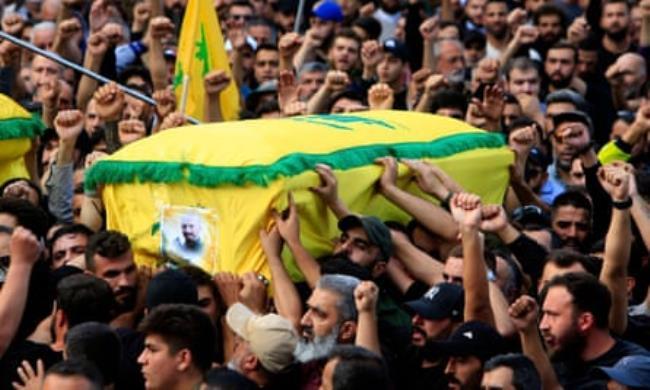 People carry a casket of a Hezbollah member killed in Israeli strikes, draped in yellow and green Hezbollah flags, during a funeral in the town of Khirbet Selm, southern Lebanon, on Oct. 10, 2023