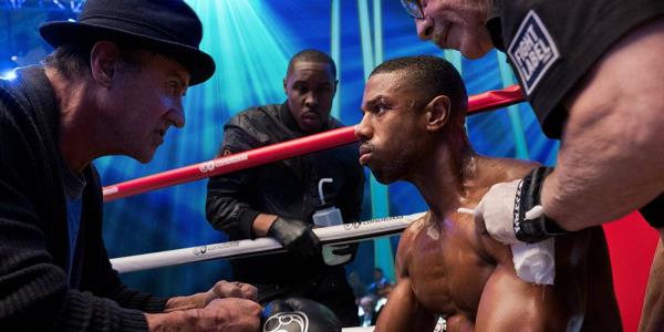 Ado<em></em>nis Creed sitting on a stool staring at Rocky Balboa during a fight in creed 2.