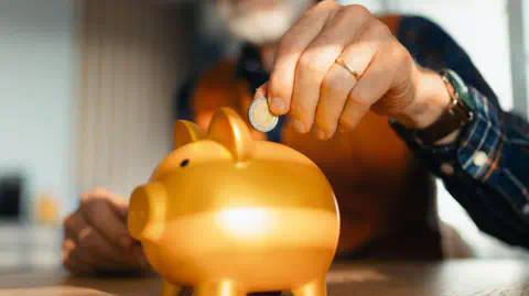 Getty Images Man placing euro coin into a golden piggy bank